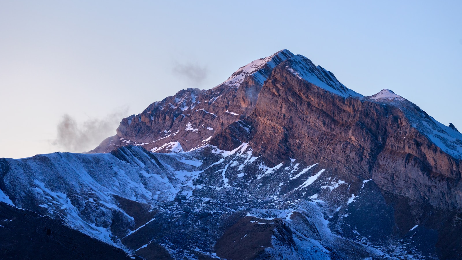 A snow covered mountain with a blue sky in the background